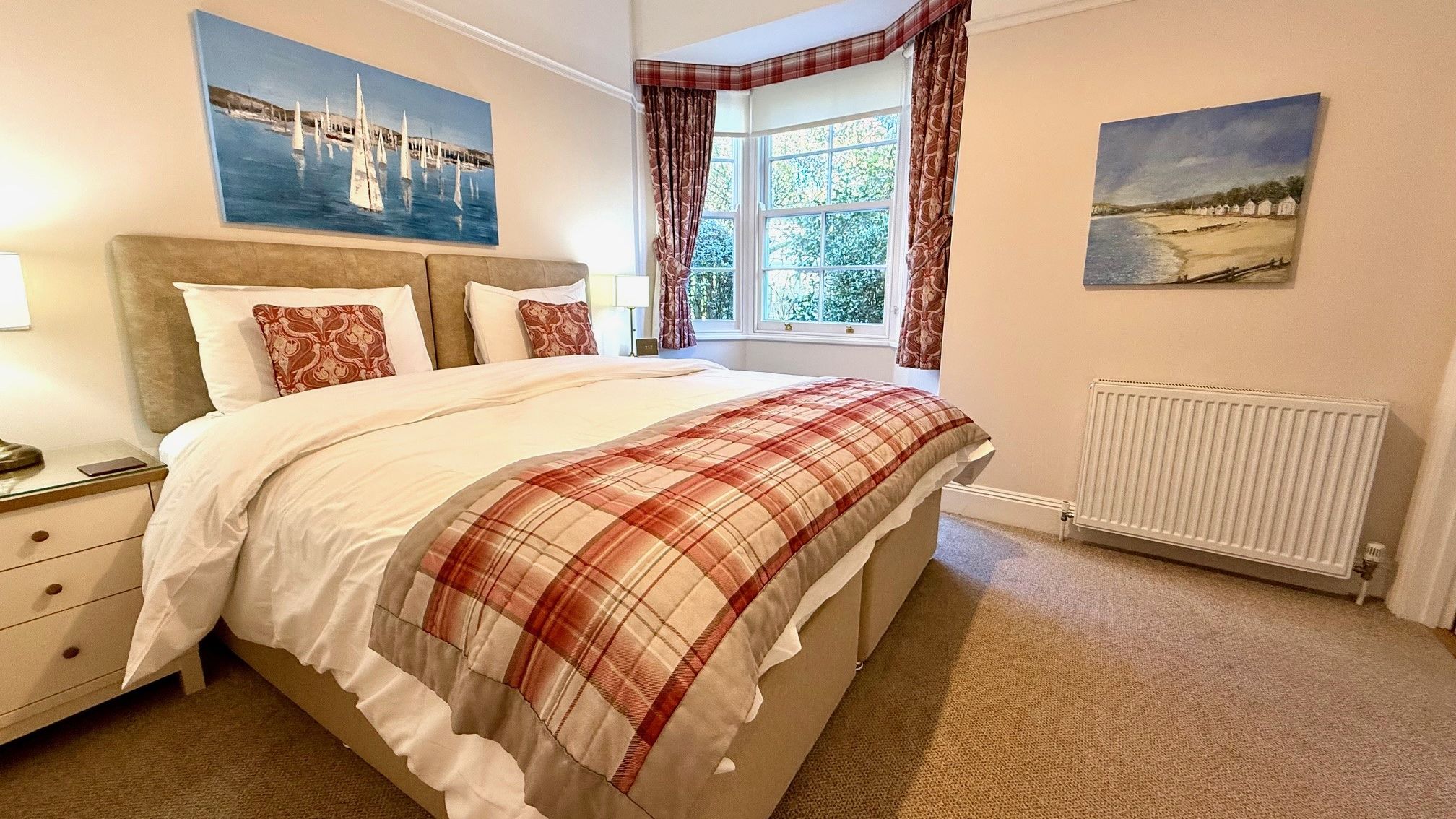 Ground floor bedroom with double bed, plaid throw and bay window