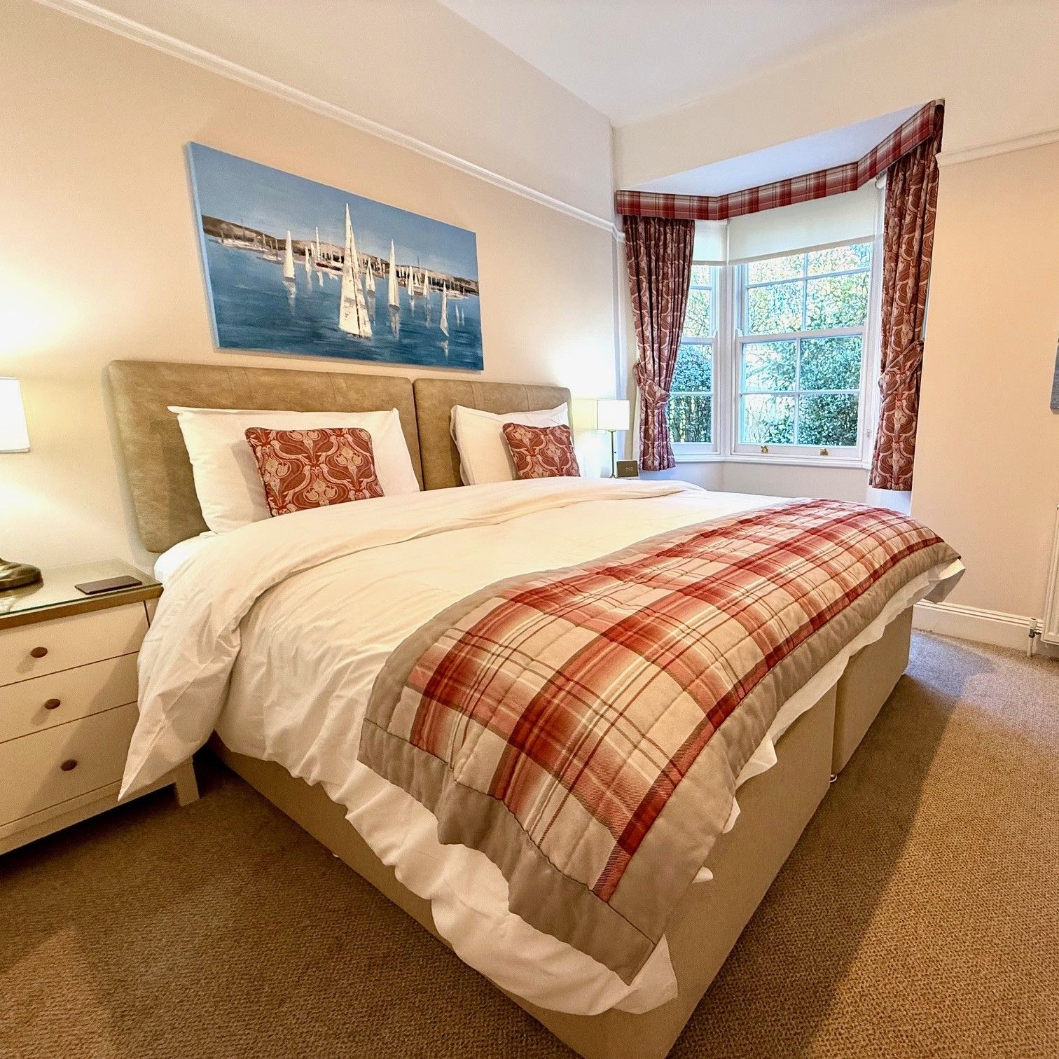 Ground floor bedroom with double bed, plaid throw and bay window
