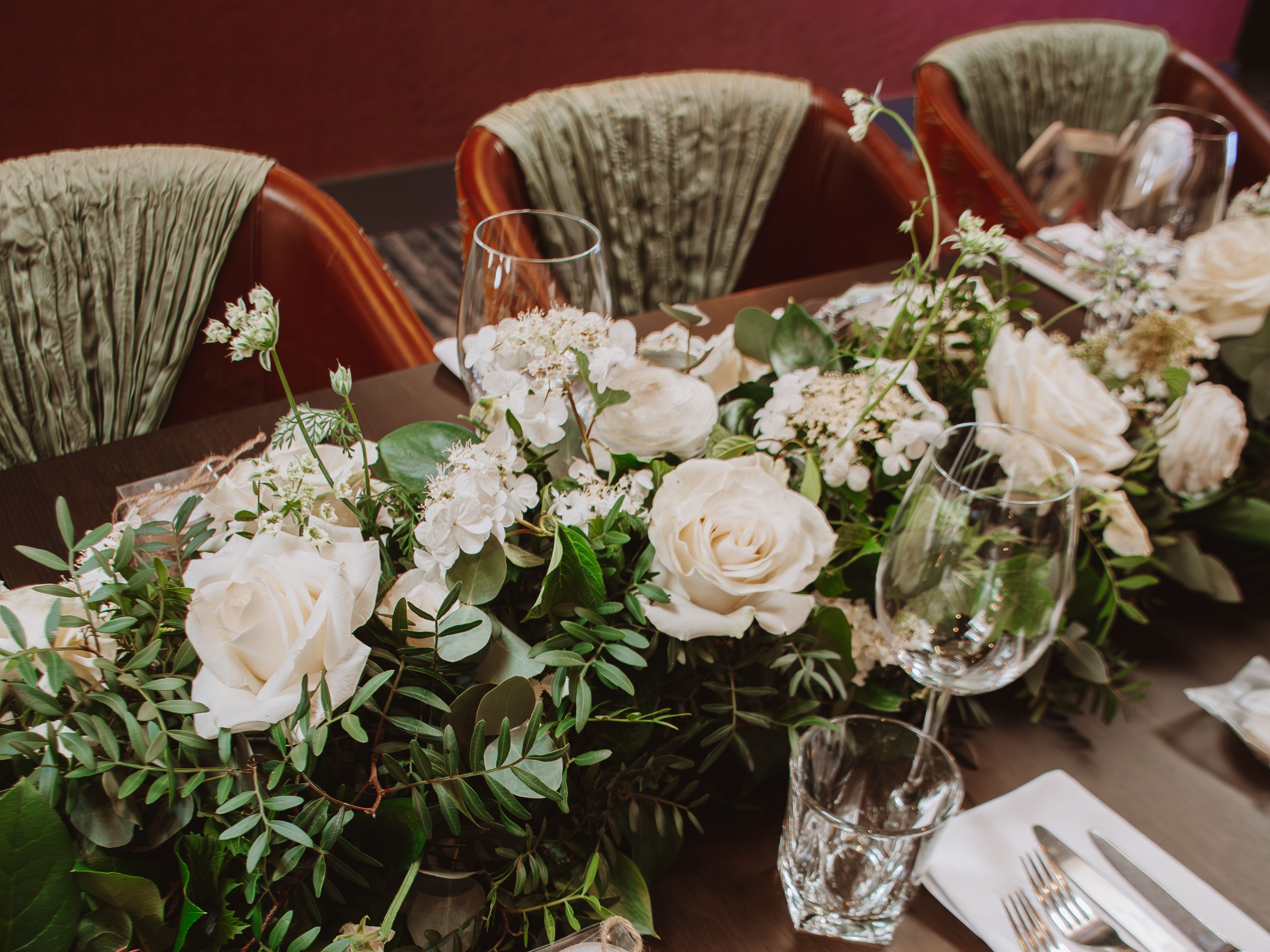 Elegant wedding table setting with white roses, greenery, and personalized gifts.