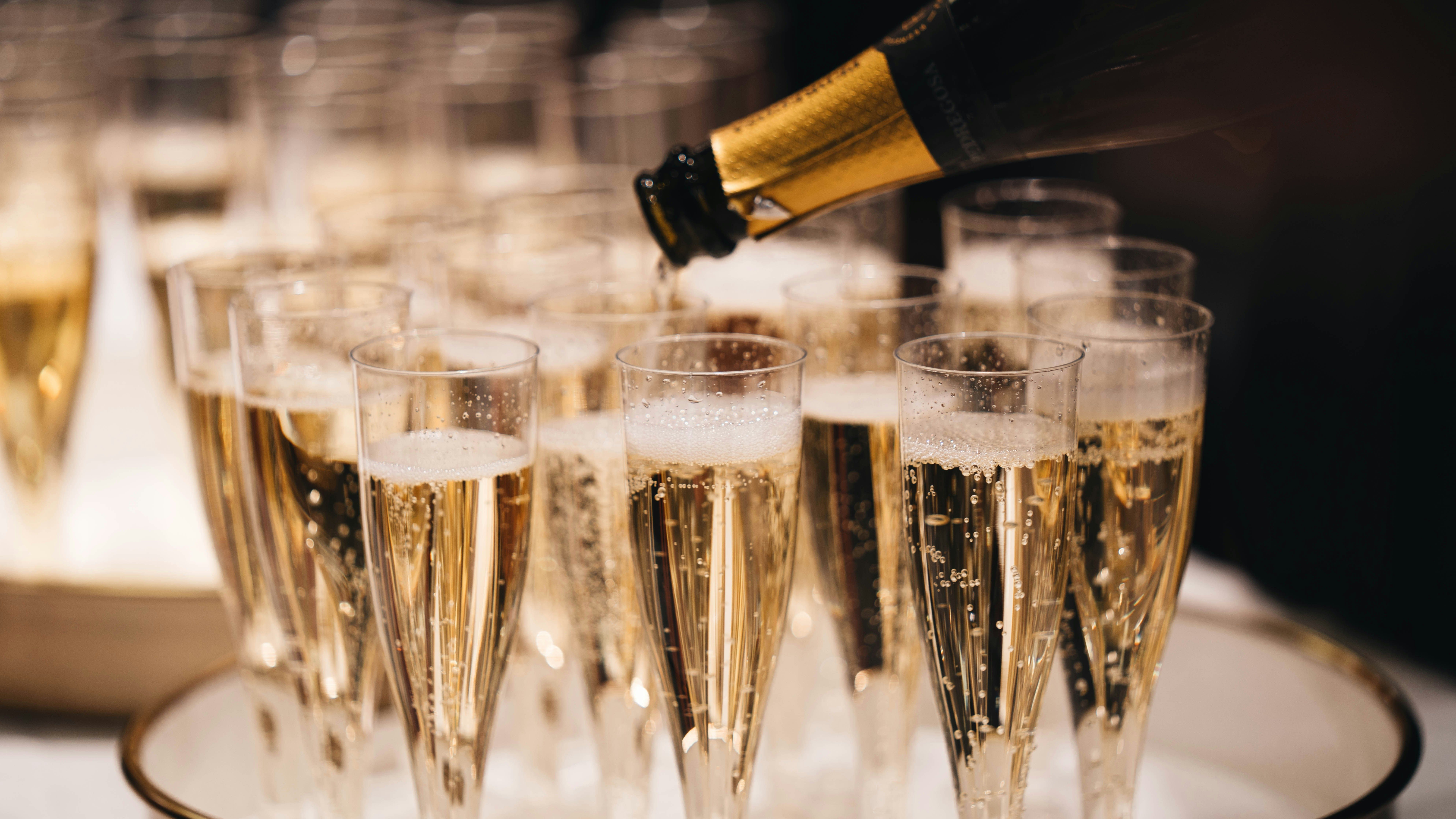 Champagne being poured from a bottle into multiple glasses