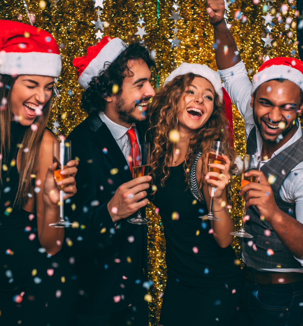 Group of friends wearing Santa hats celebrating at a festive party with champagne and confetti