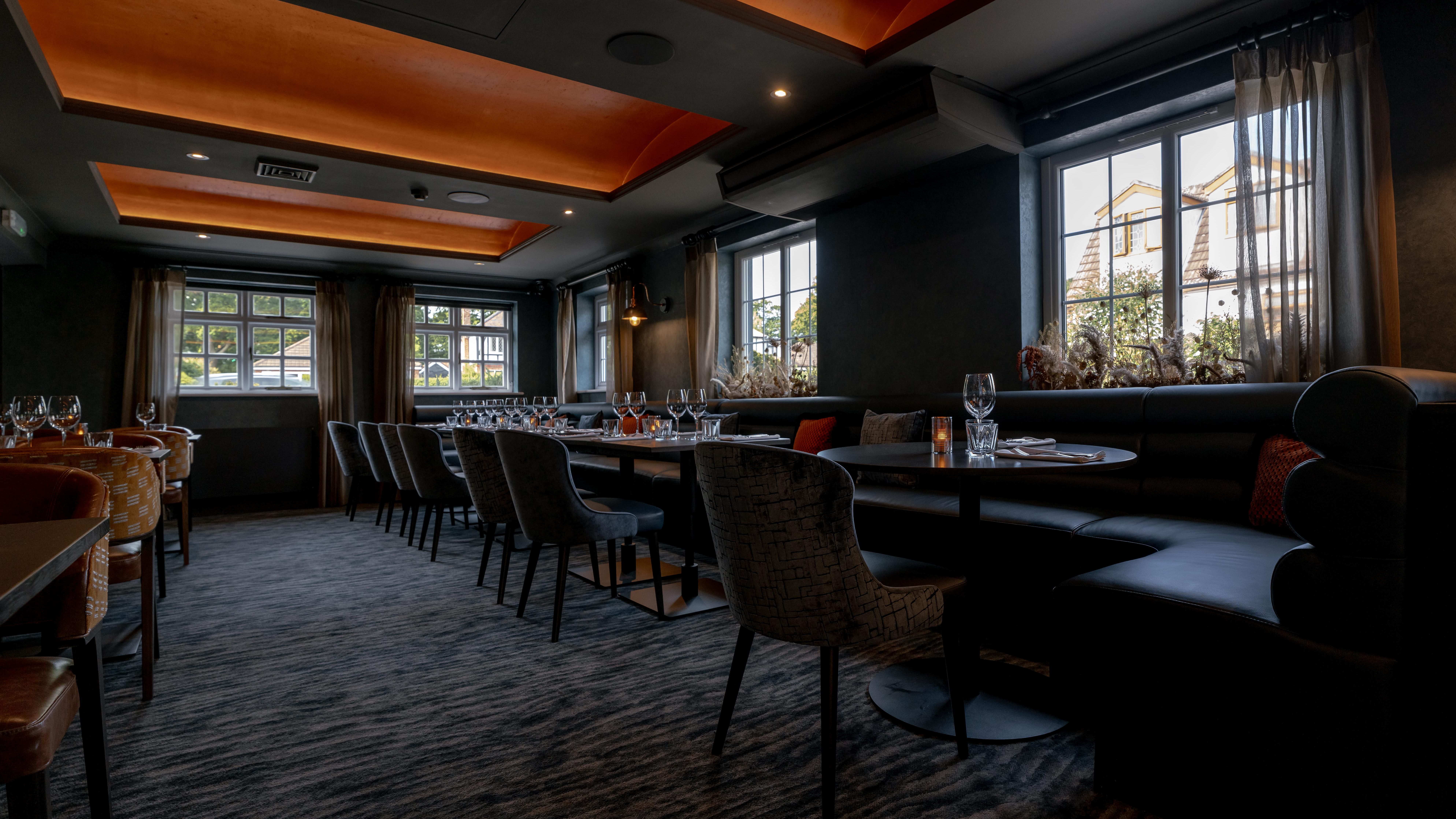 Modern dining room with set tables, cushioned chairs, and large windows letting in natural light.