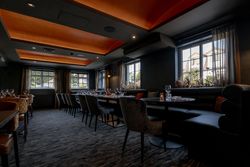 Modern dining room with set tables, cushioned chairs, and large windows letting in natural light.