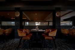 Modern dining area in a restaurant with brown leather chairs and set tables.