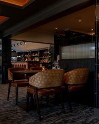 Modern restaurant dining area with brown chairs and a well-stocked bar in the background