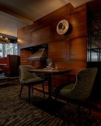 Intimate dining table for two in a cozy restaurant setting with a modern fireplace and elegant décor.
