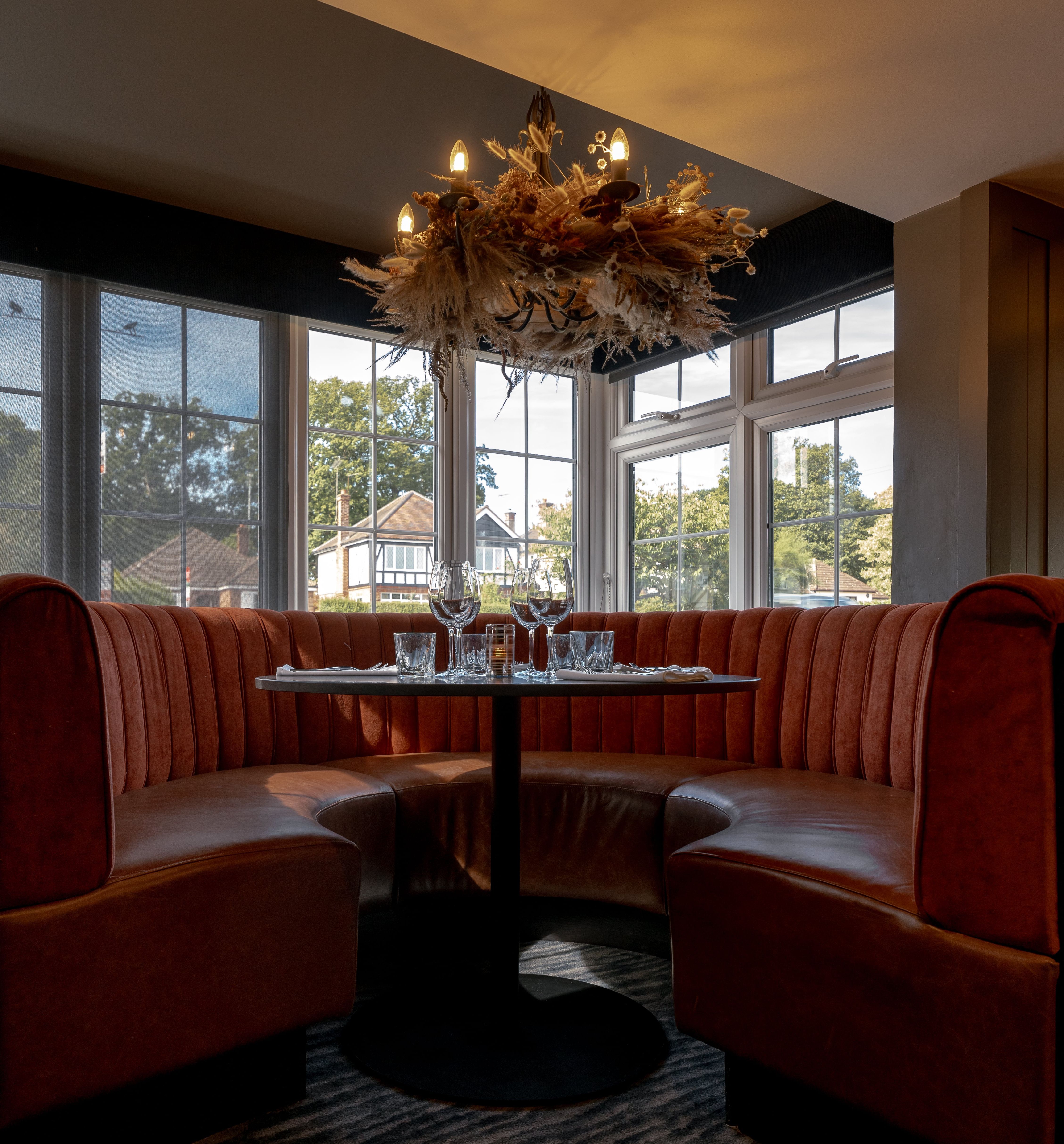Cozy dining booth with red velvet seating, set table, and decorative chandelier in a restaurant