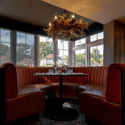 Cozy dining booth with red velvet seating, set table, and decorative chandelier in a restaurant
