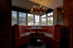 Cozy dining booth with red velvet seating, set table, and decorative chandelier in a restaurant