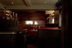 Elegant restaurant dining booth with red velvet seating, set with glassware and a small lamp on the table.