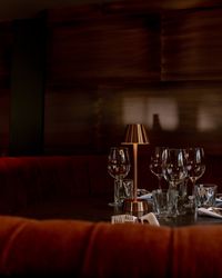Elegant dining booth with red velvet seating, set table with glassware and a small lamp