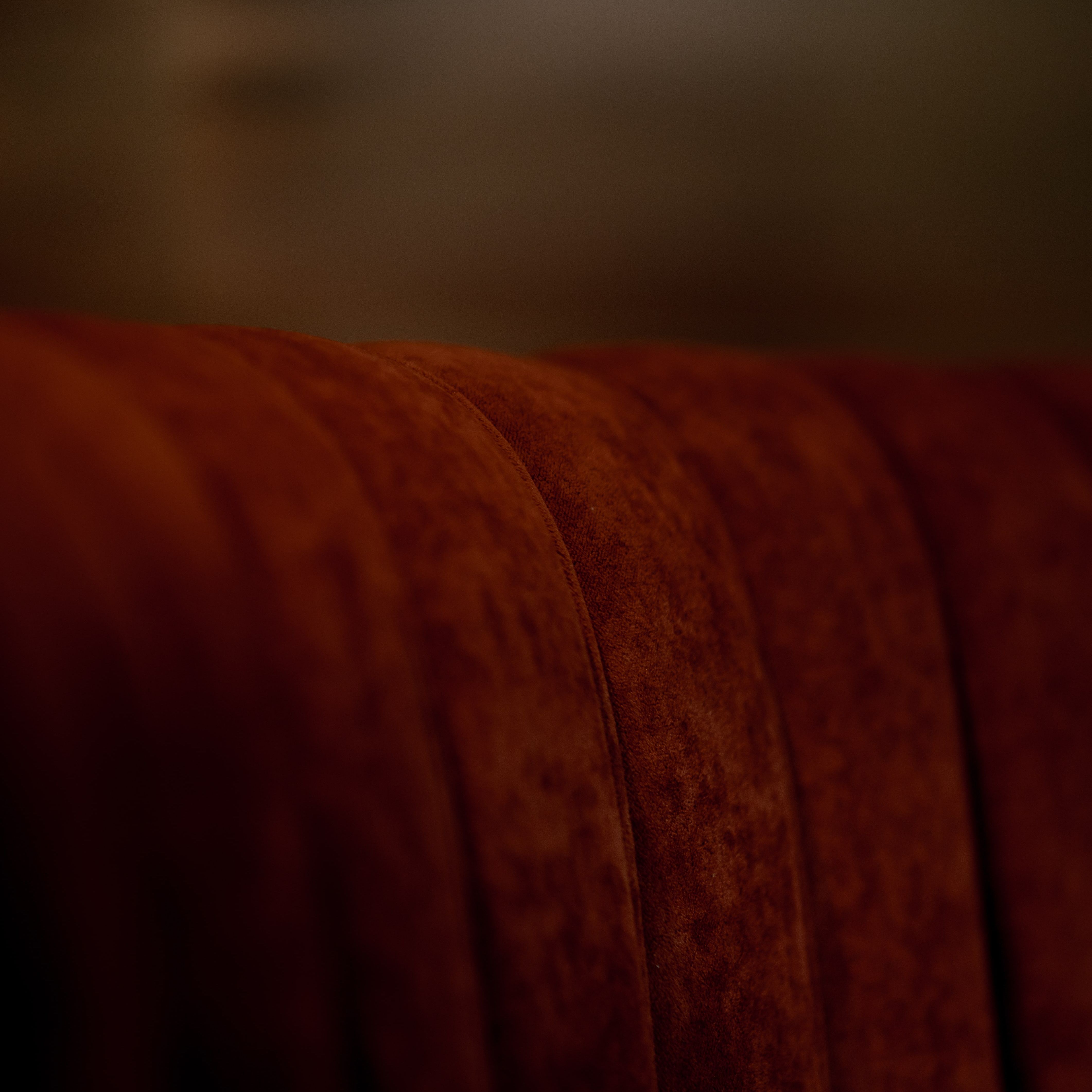 Close-up view of a plush, red velvet booth seat with vertical channel tufting