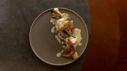 Gourmet seafood dish with prawns, mussels, and creamy sauce on a dark plate