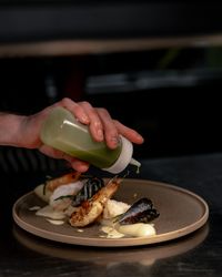 Chef drizzling green sauce on a seafood dish with shrimp and mussels