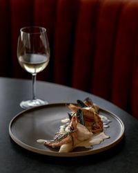 Gourmet seafood dish with prawns and mussels served with a glass of white wine on a dark table.