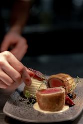 Plated gourmet dish being carefully garnished by a chef's hand