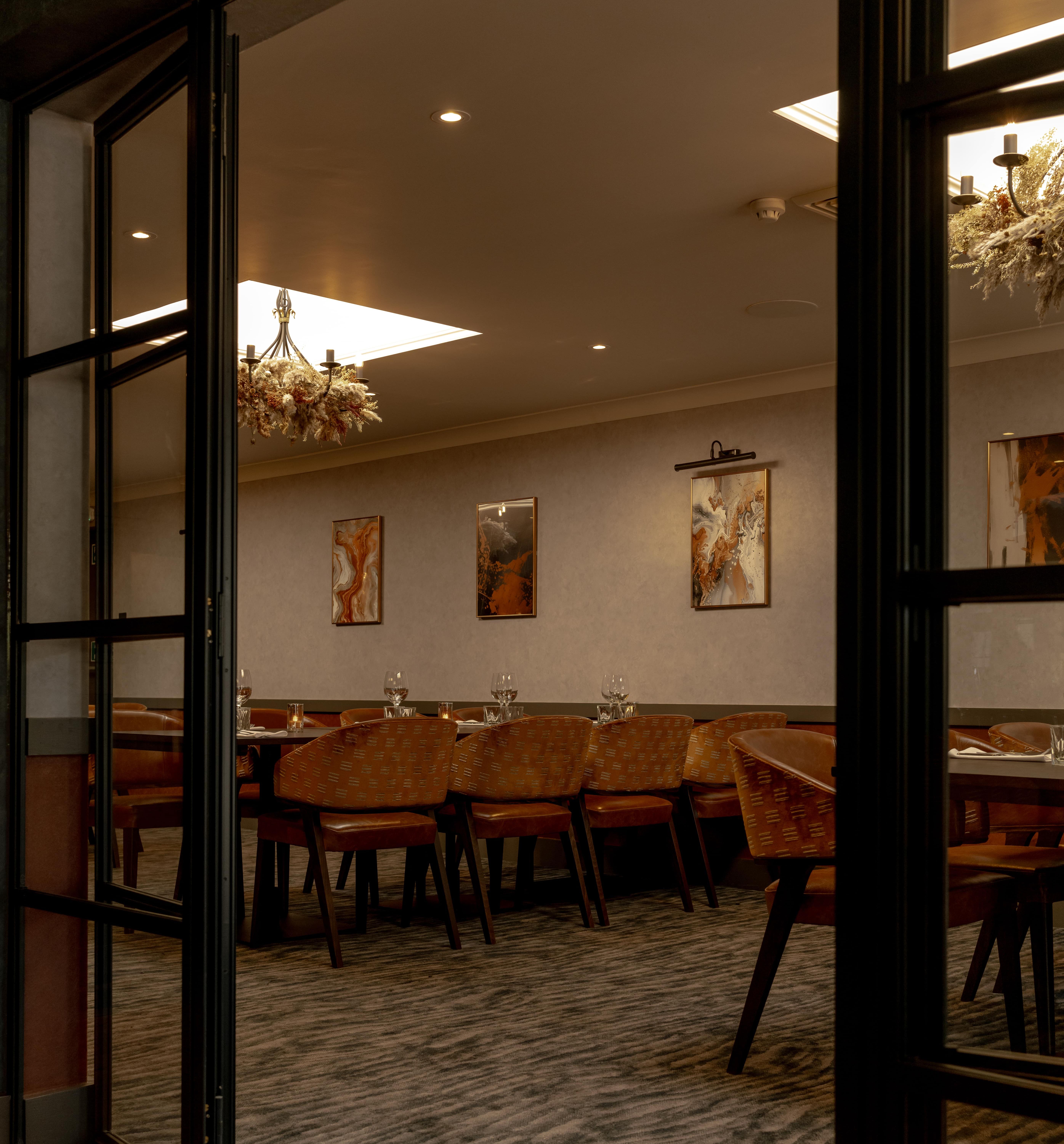 Elegant private dining room with modern decor, large table, and warm lighting