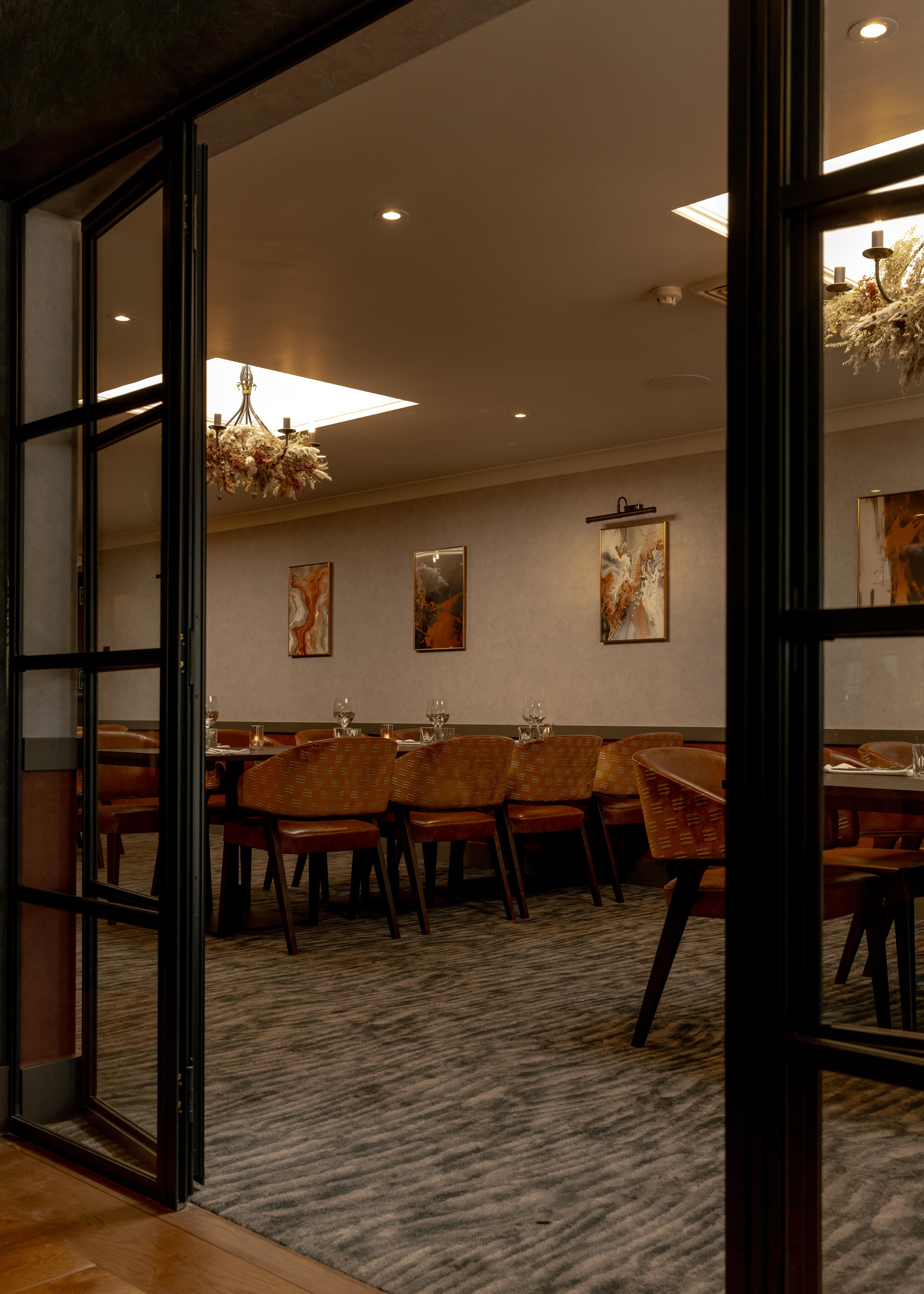 Elegant private dining room with modern decor, large table, and warm lighting