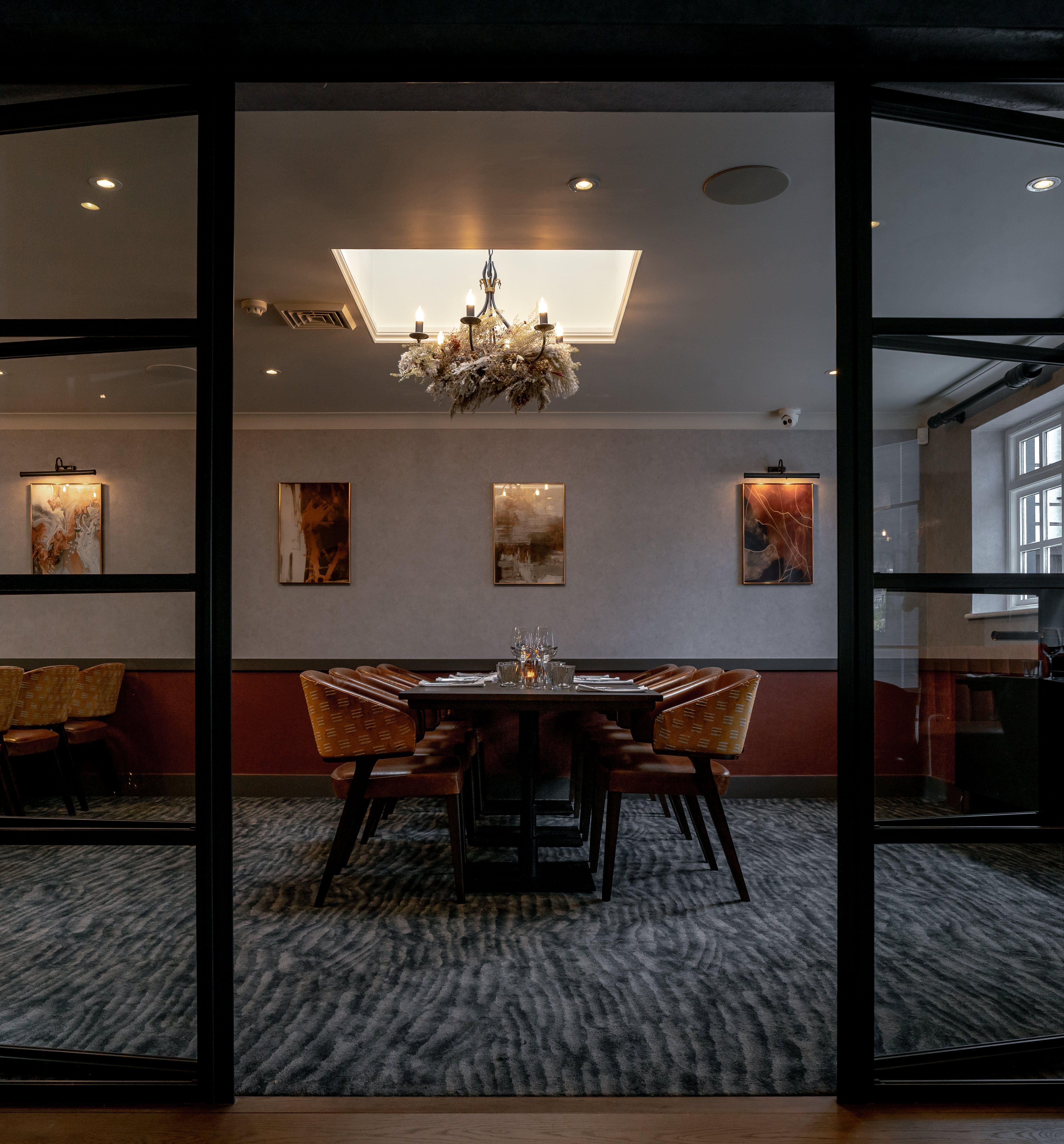 Elegant private dining room set up for a meal with a chandelier and modern art on the walls