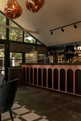 Modern bar area with pink and black arched counter and hanging glass lighting fixtures