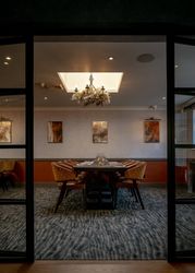 Elegant private dining room with modern decor and a chandelier, featuring a large table surrounded by chairs.
