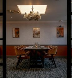 Elegant private dining room with a set dining table, chandelier, and modern artwork on the wall.
