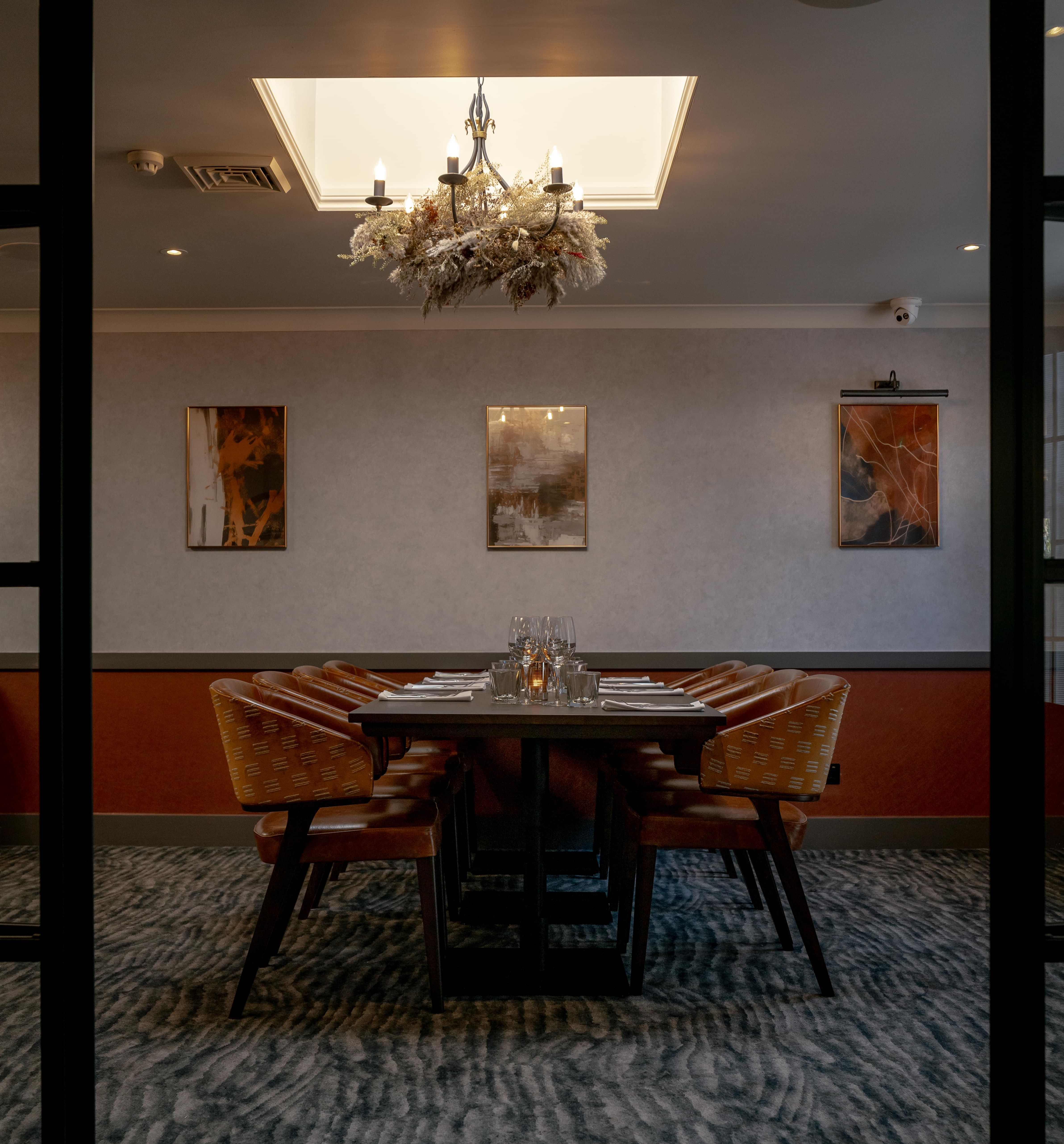 Elegant private dining room with a set dining table, chandelier, and modern artwork on the wall.
