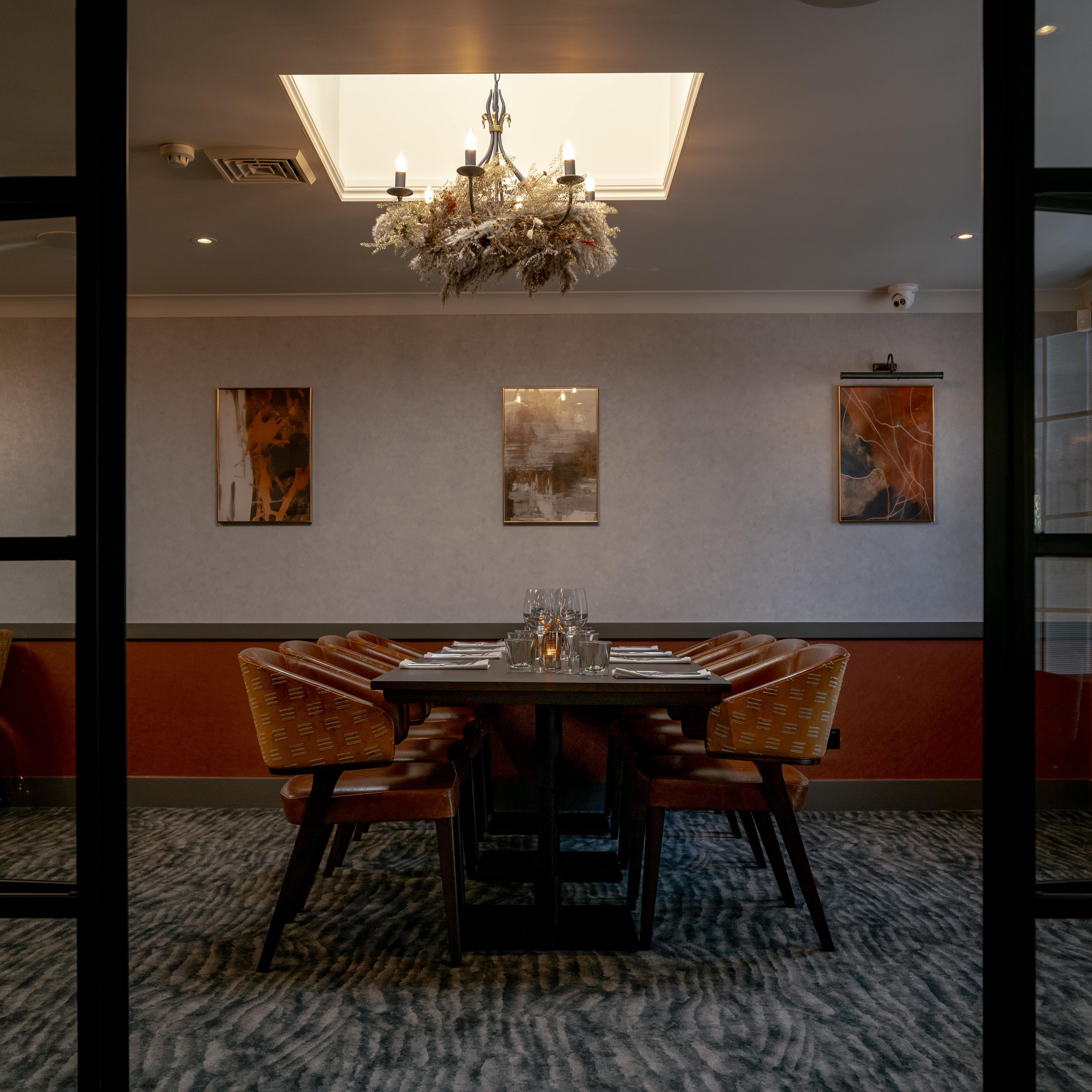 Elegant private dining room with a set dining table, chandelier, and modern artwork on the wall.