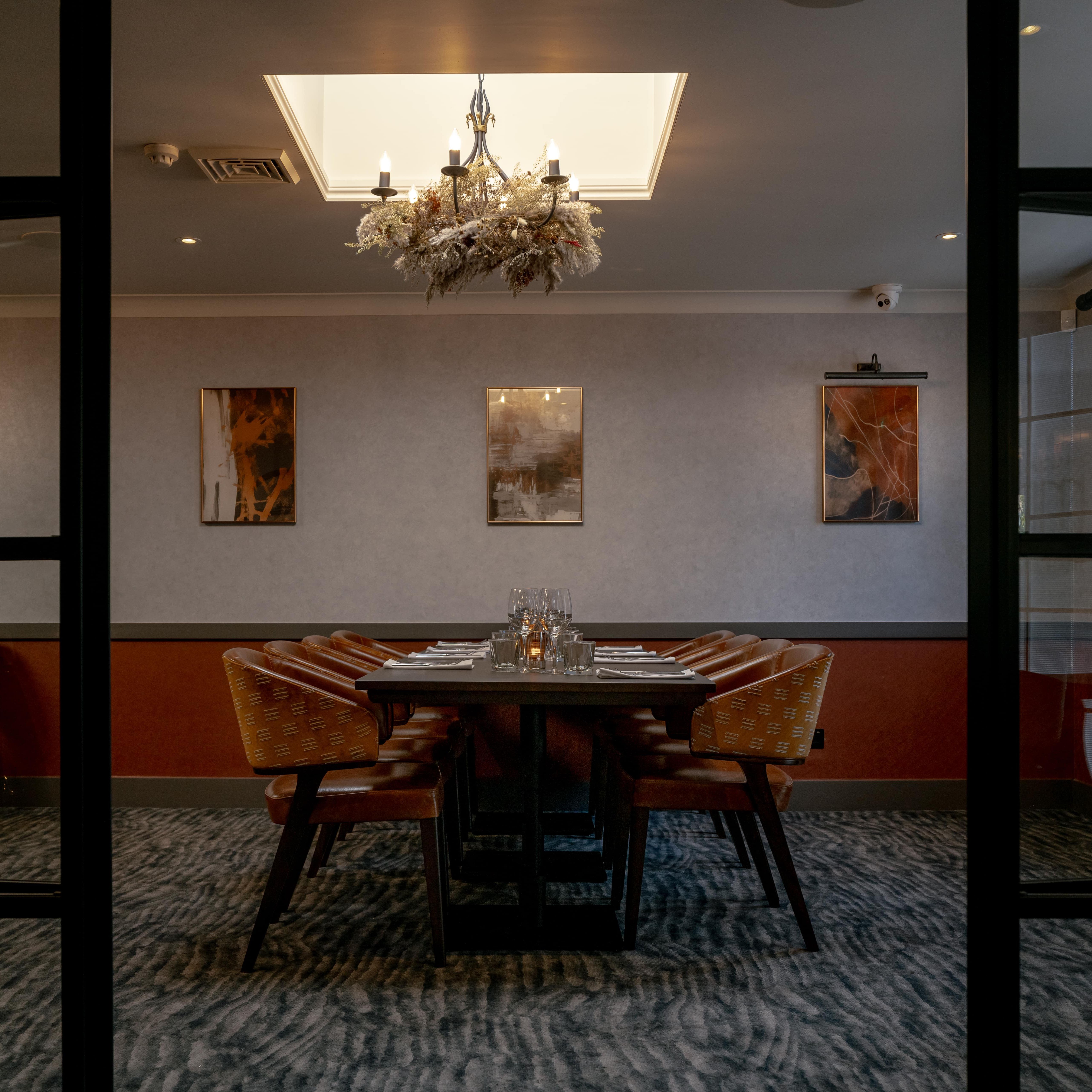 Elegant private dining room with a set dining table, chandelier, and modern artwork on the wall.
