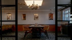Elegant private dining room with a set dining table, chandelier, and modern artwork on the wall.