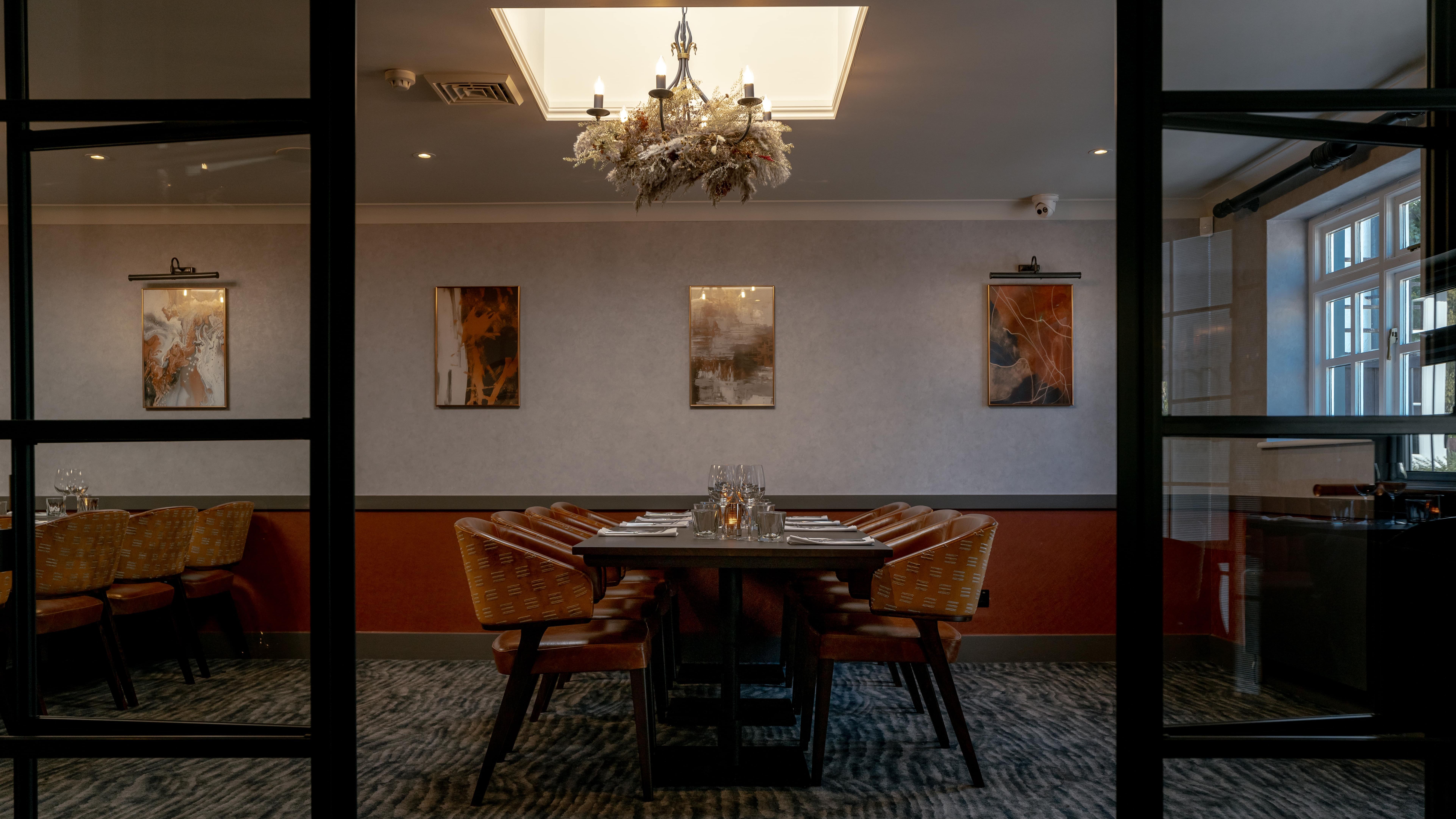Elegant private dining room with a set dining table, chandelier, and modern artwork on the wall.