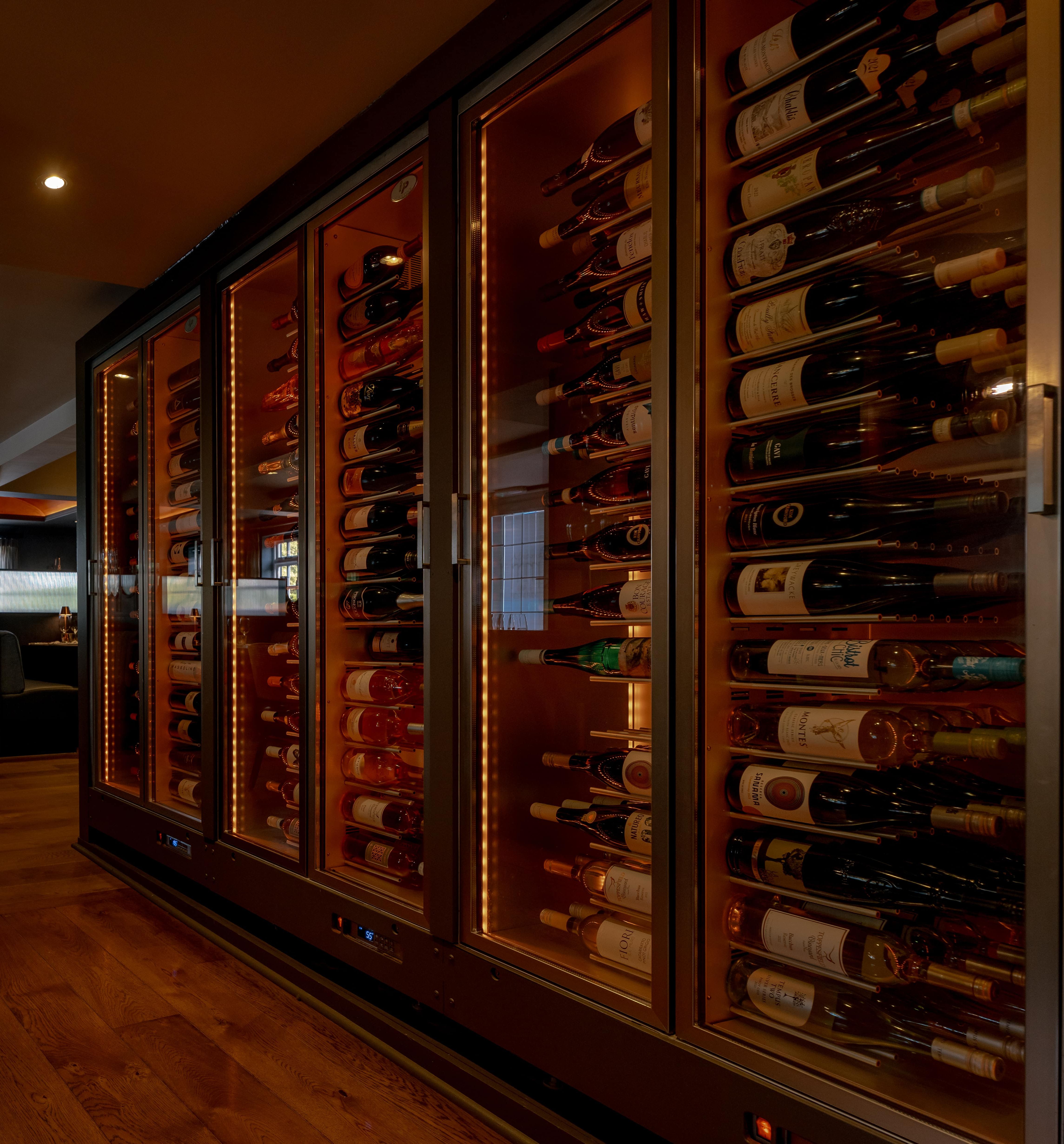 Modern restaurant interior with a glass wine cellar and cozy dining booths