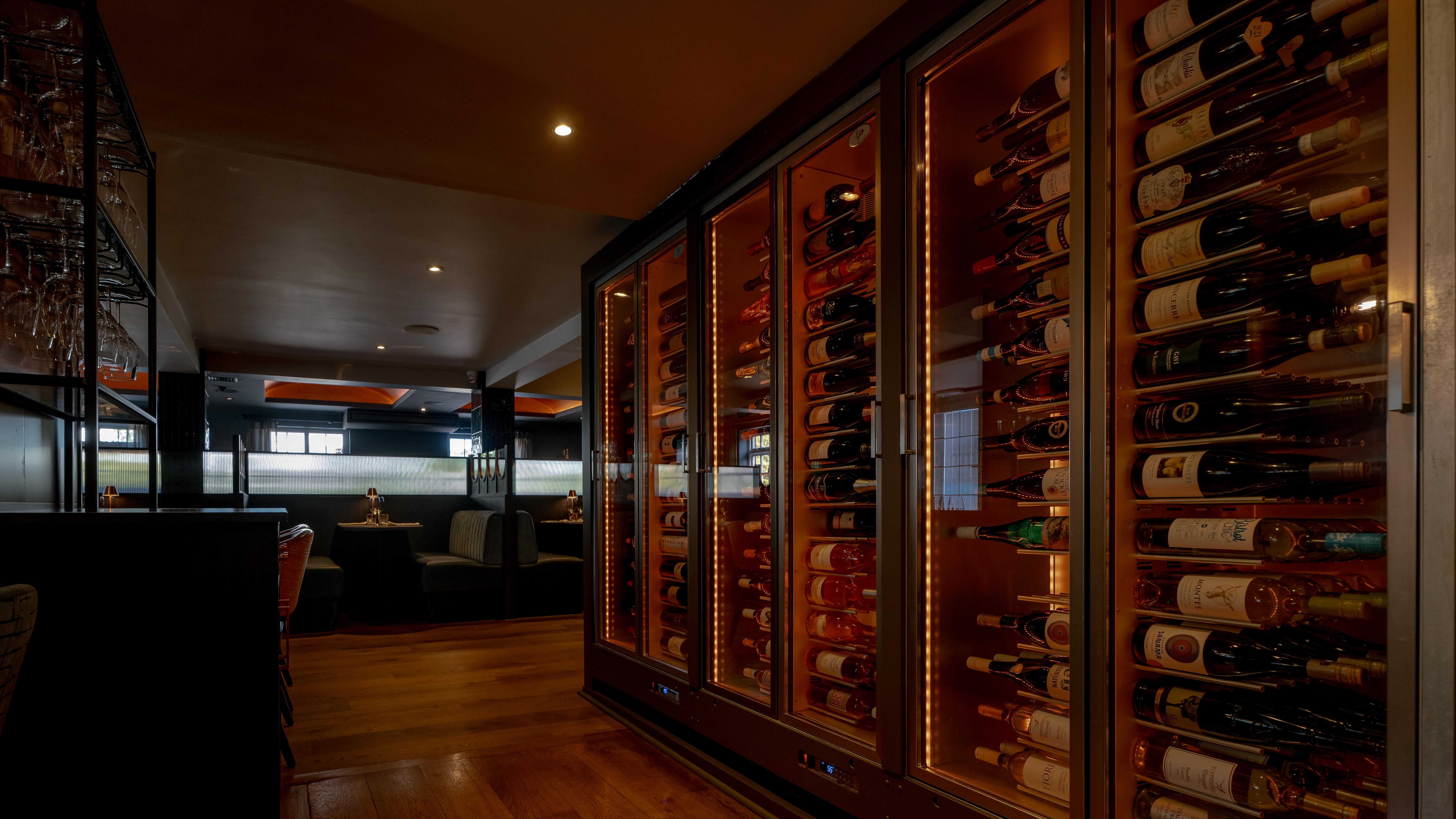Modern restaurant interior with a glass wine cellar and cozy dining booths