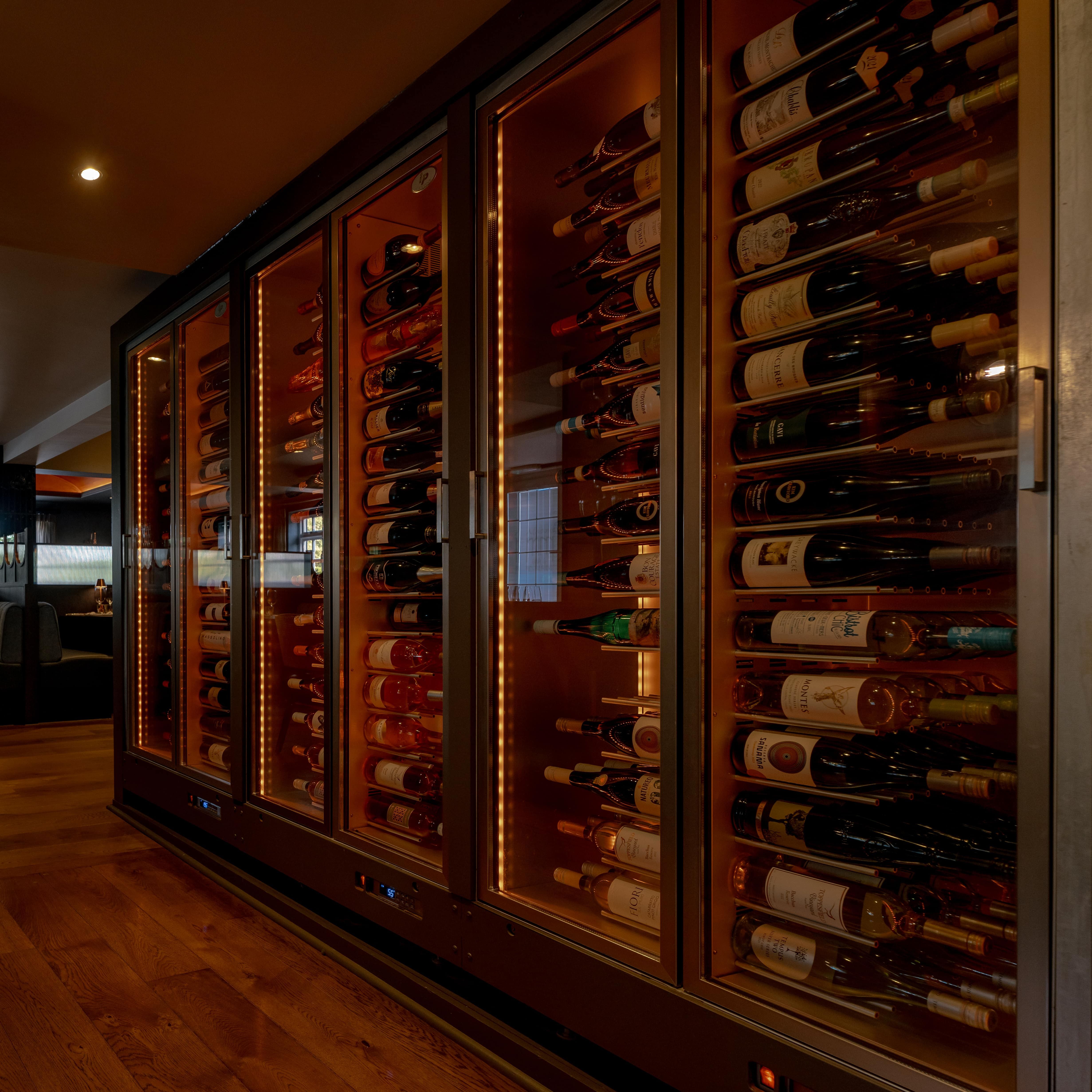 Modern restaurant interior with a glass wine cellar and cozy dining booths