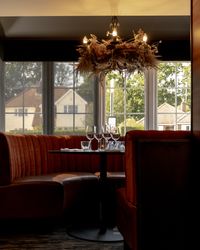 Elegant restaurant booth with red velvet seating, set table, and decorative chandelier