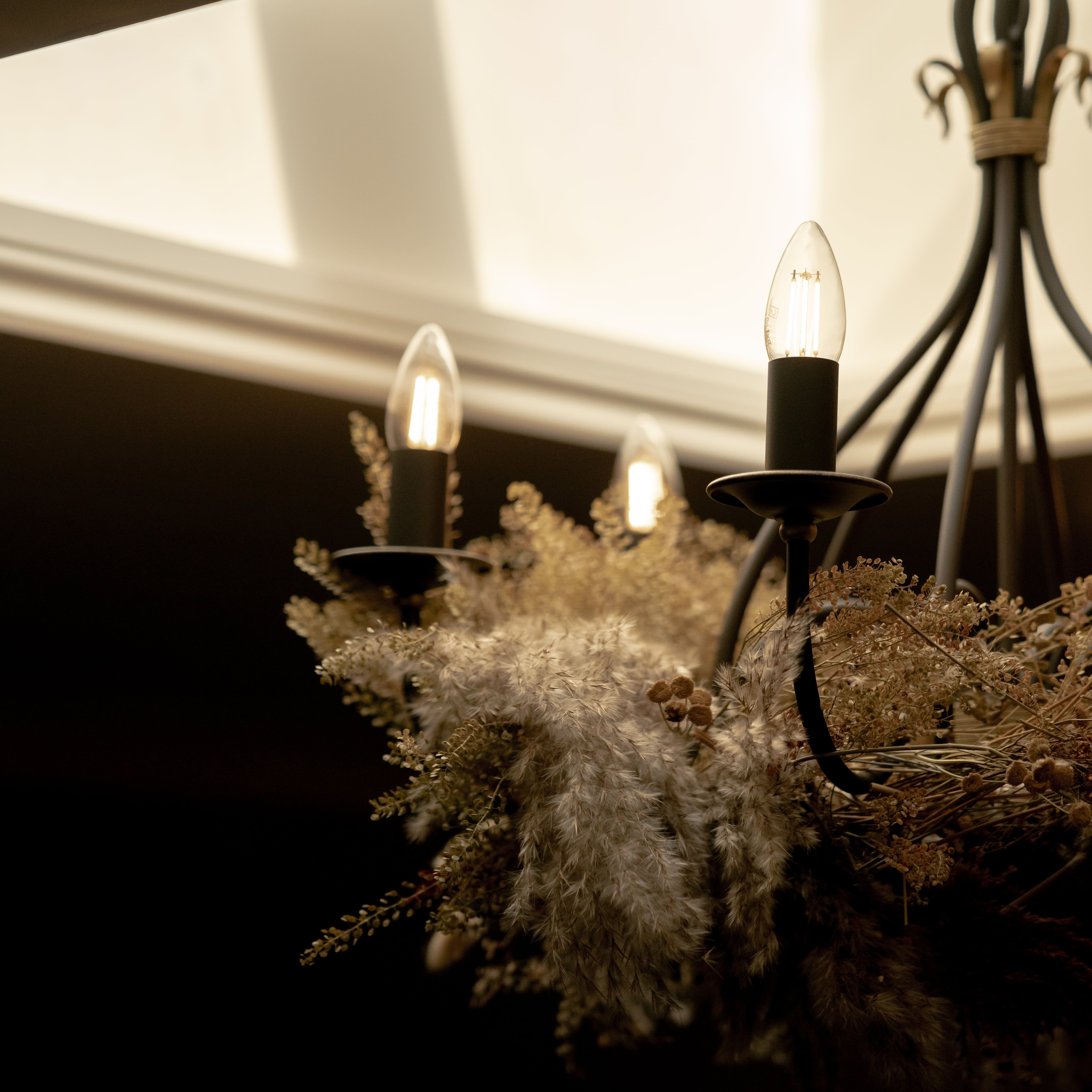 Decorative chandelier with glowing bulbs and dried floral arrangement