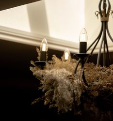 Decorative chandelier with glowing bulbs and dried floral arrangement