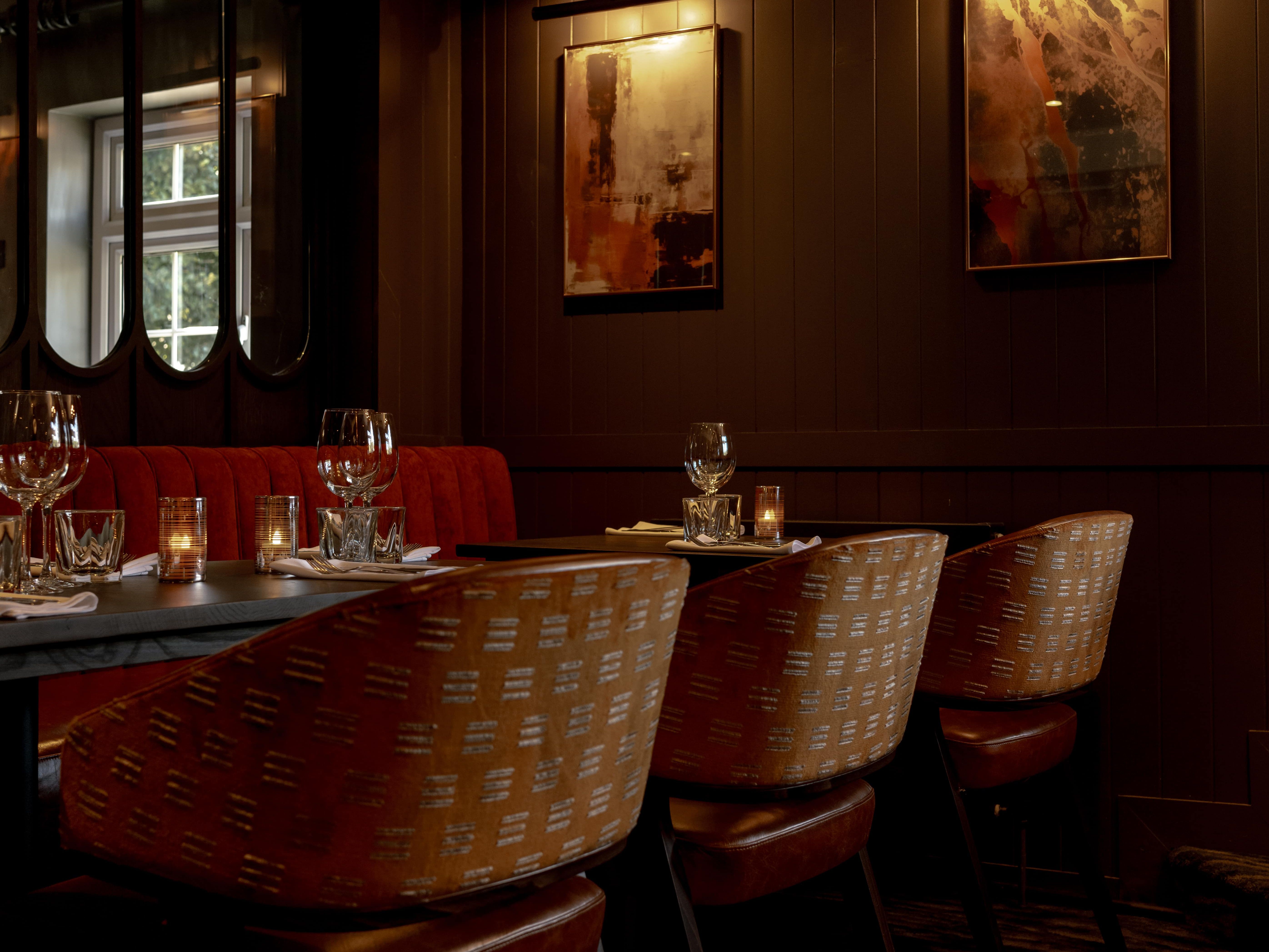 Elegant restaurant interior with dim lighting, set tables, and abstract art on the walls.