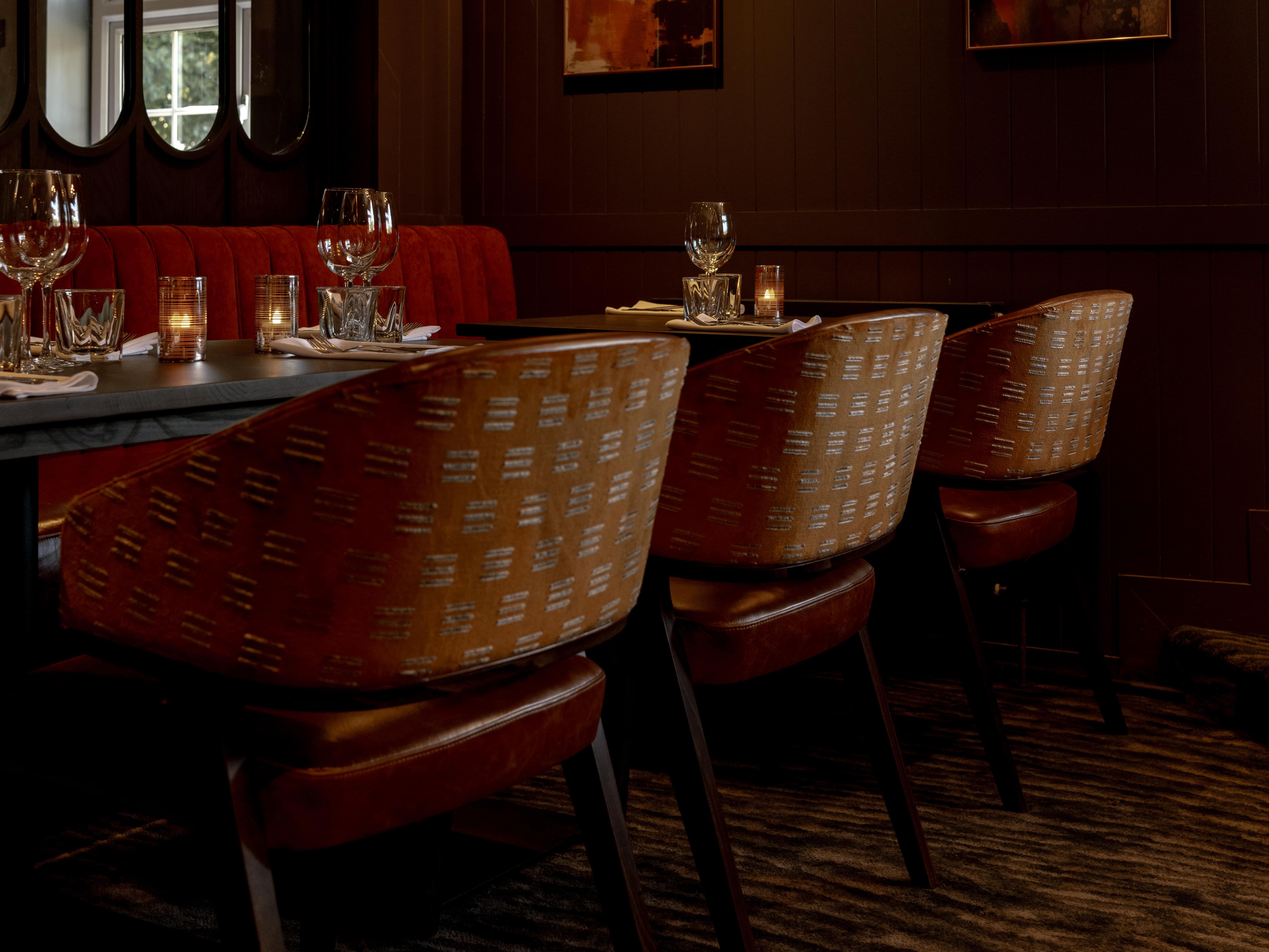 Elegant restaurant interior with dim lighting, set tables, and abstract art on the walls.