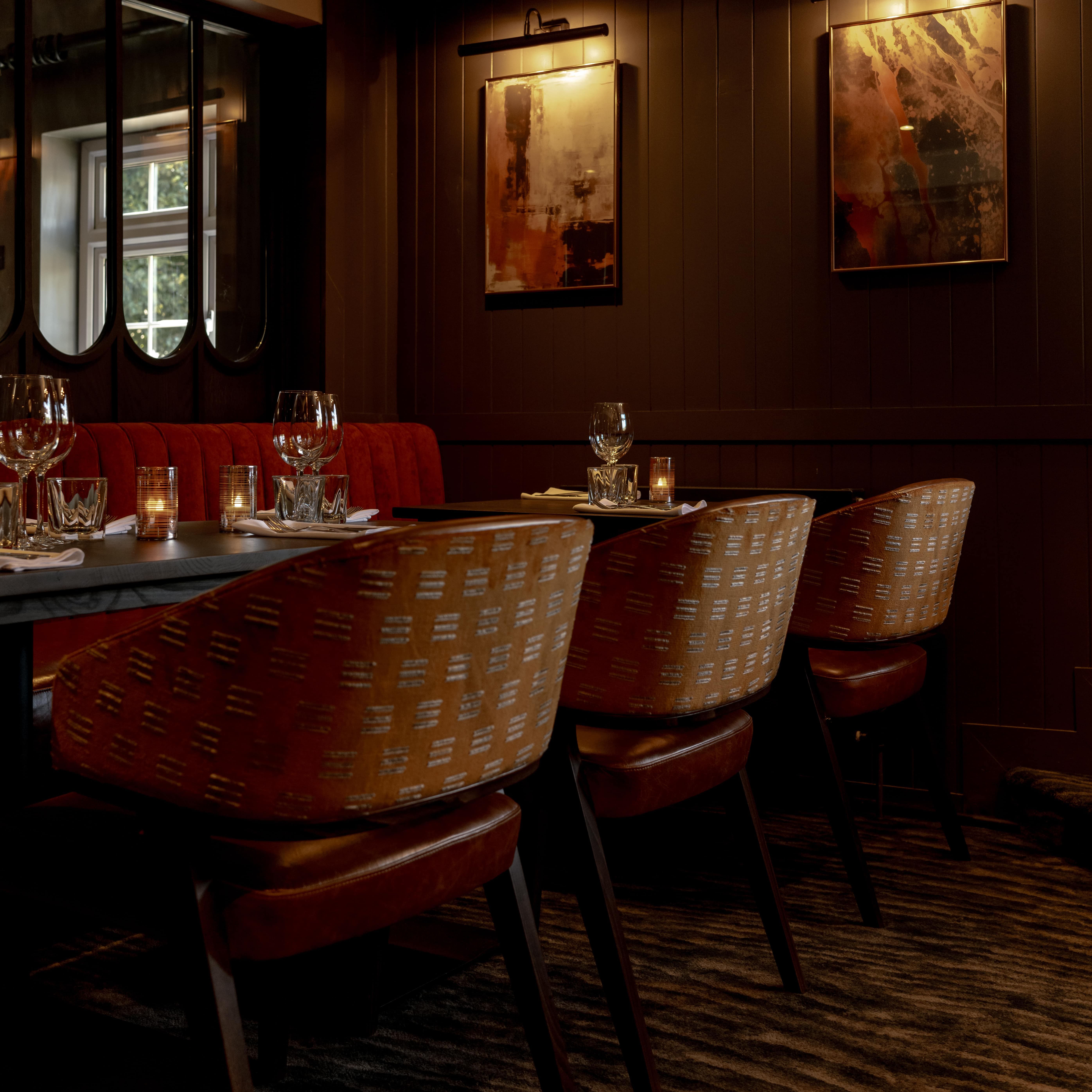 Elegant restaurant interior with dim lighting, set tables, and abstract art on the walls.