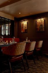 Elegant restaurant interior with dim lighting, set tables, and abstract art on the walls.