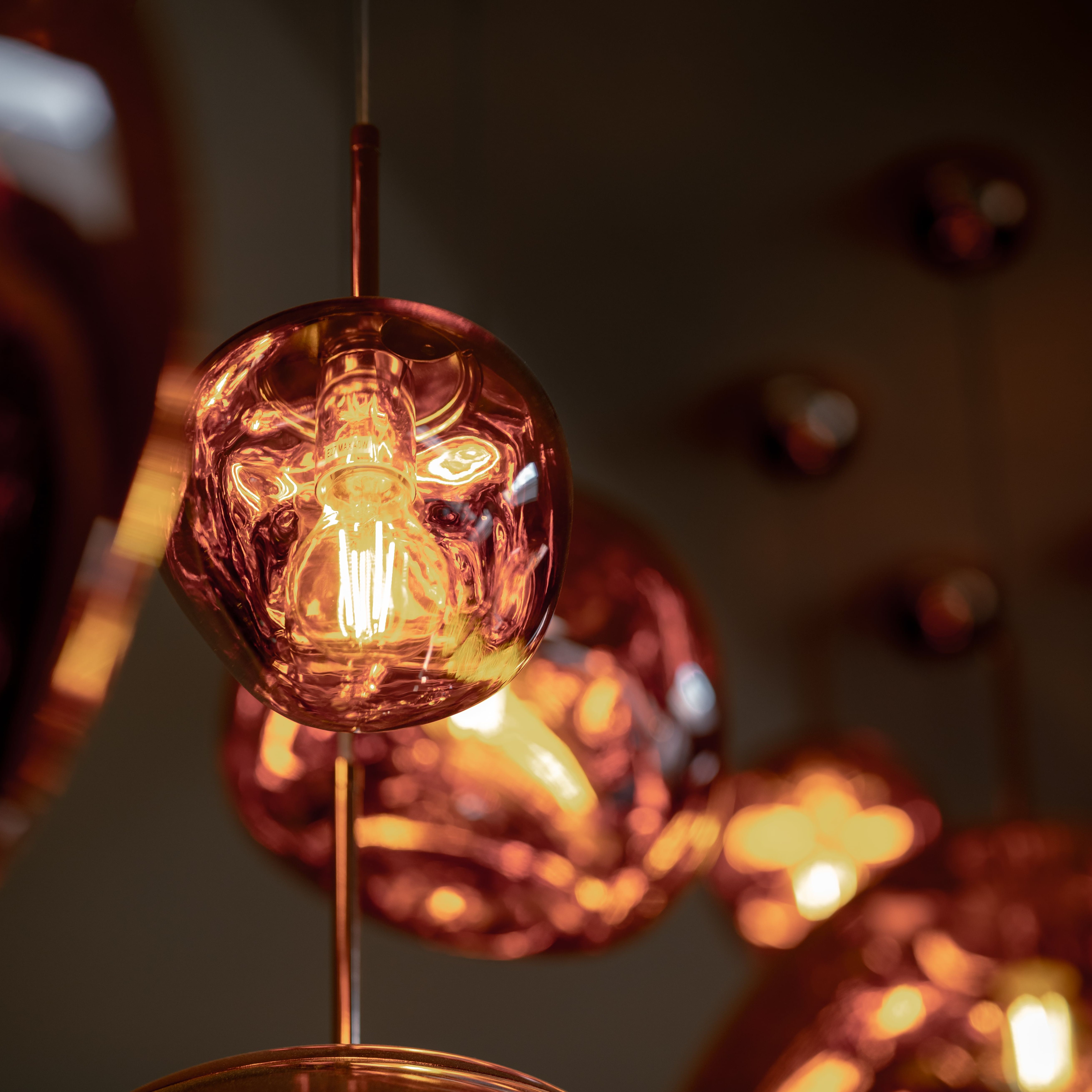 Close-up of a modern copper pendant light with an exposed filament bulb