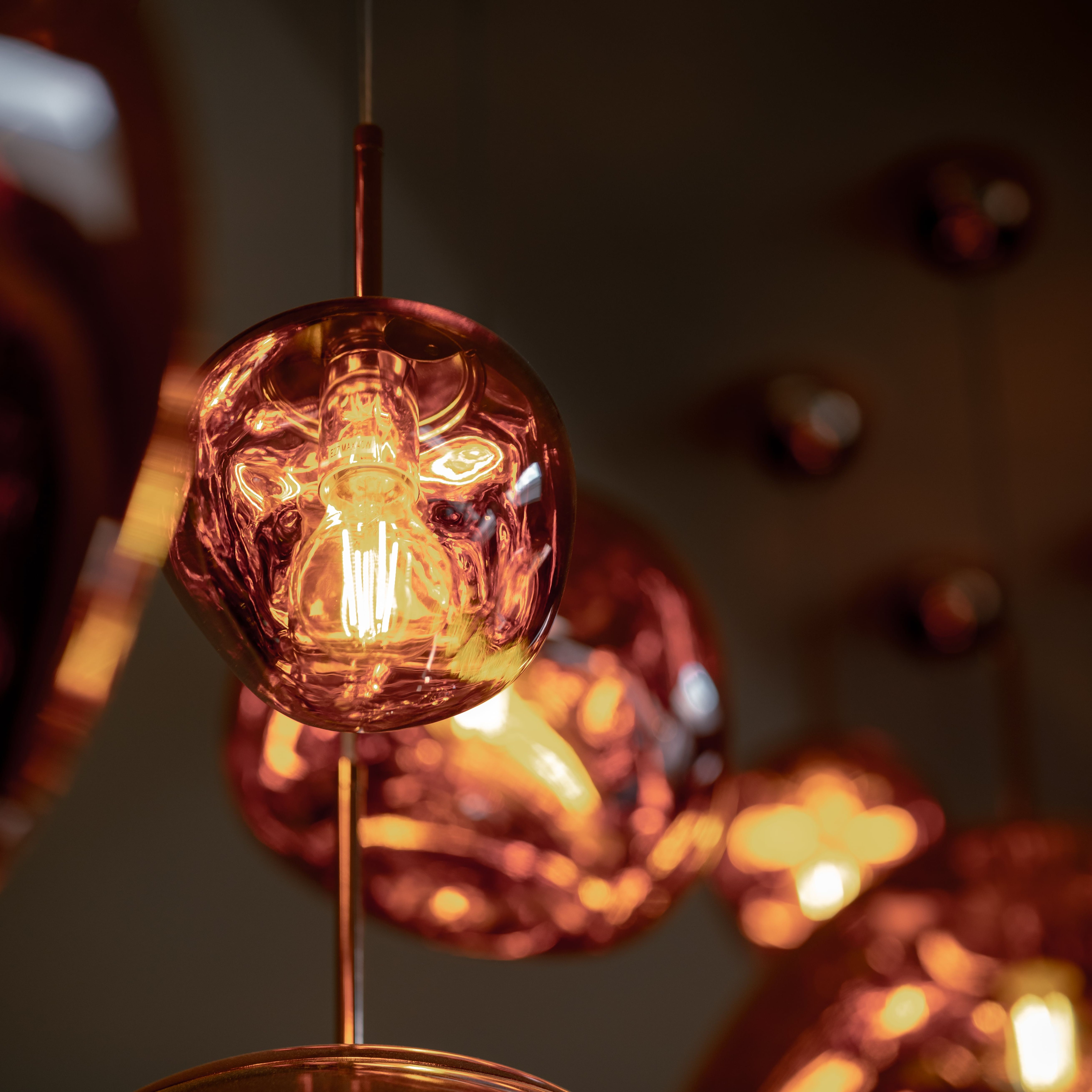Close-up of a modern copper pendant light with an exposed filament bulb