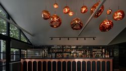 Modern bar area with unique copper pendant lights hanging from the ceiling above a stylish bar counter.