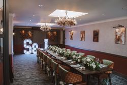Elegant banquet table with floral arrangements, decorated chairs, and light-up S & J letters at the end of the room.