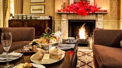 Festive afternoon tea set up in a cozy living room with a fireplace and red holiday decorations