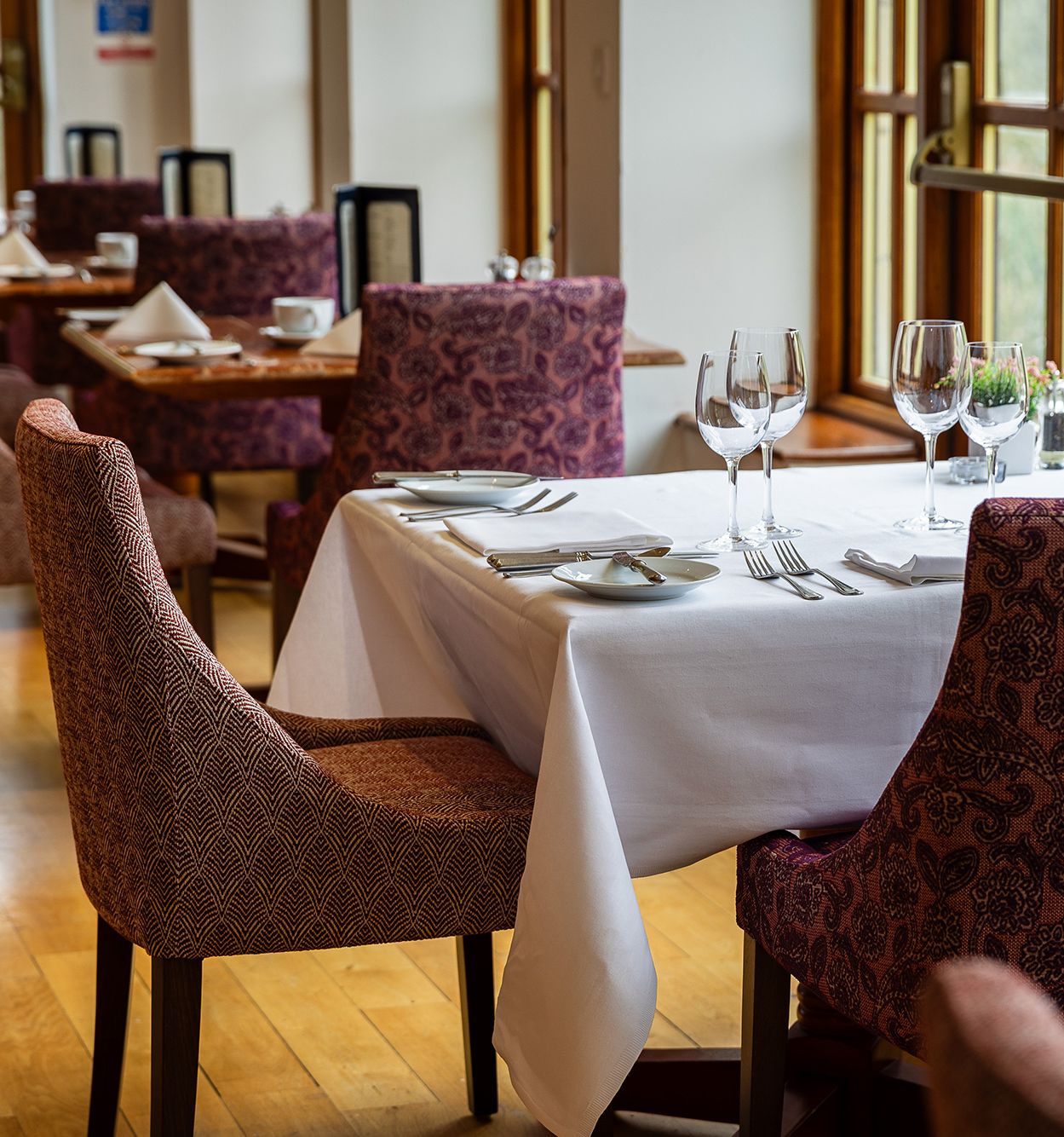restaurant table and chairs with wine glasses and menus