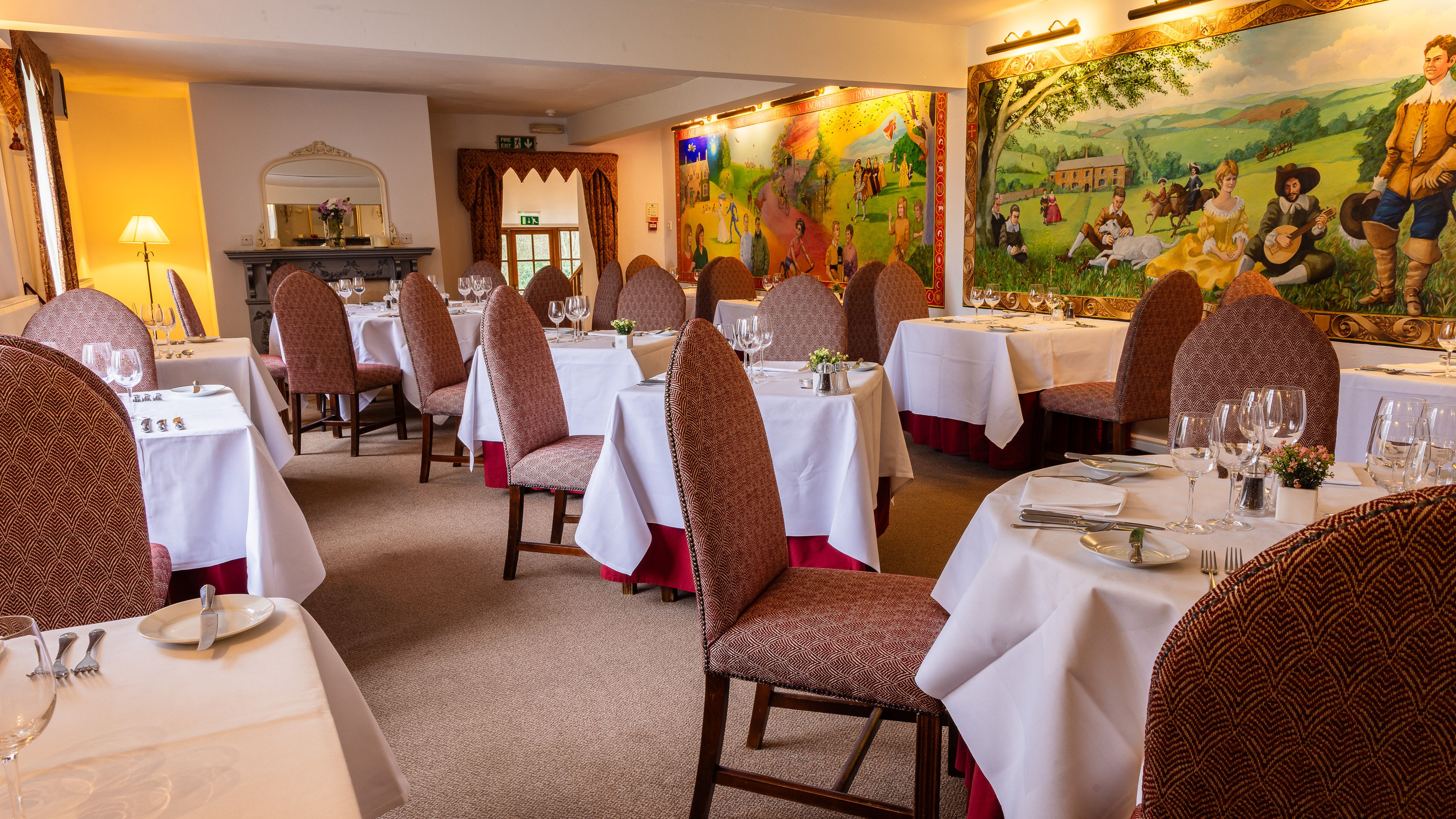 Restaurant with murals ver the walls and tablecloths on the tables