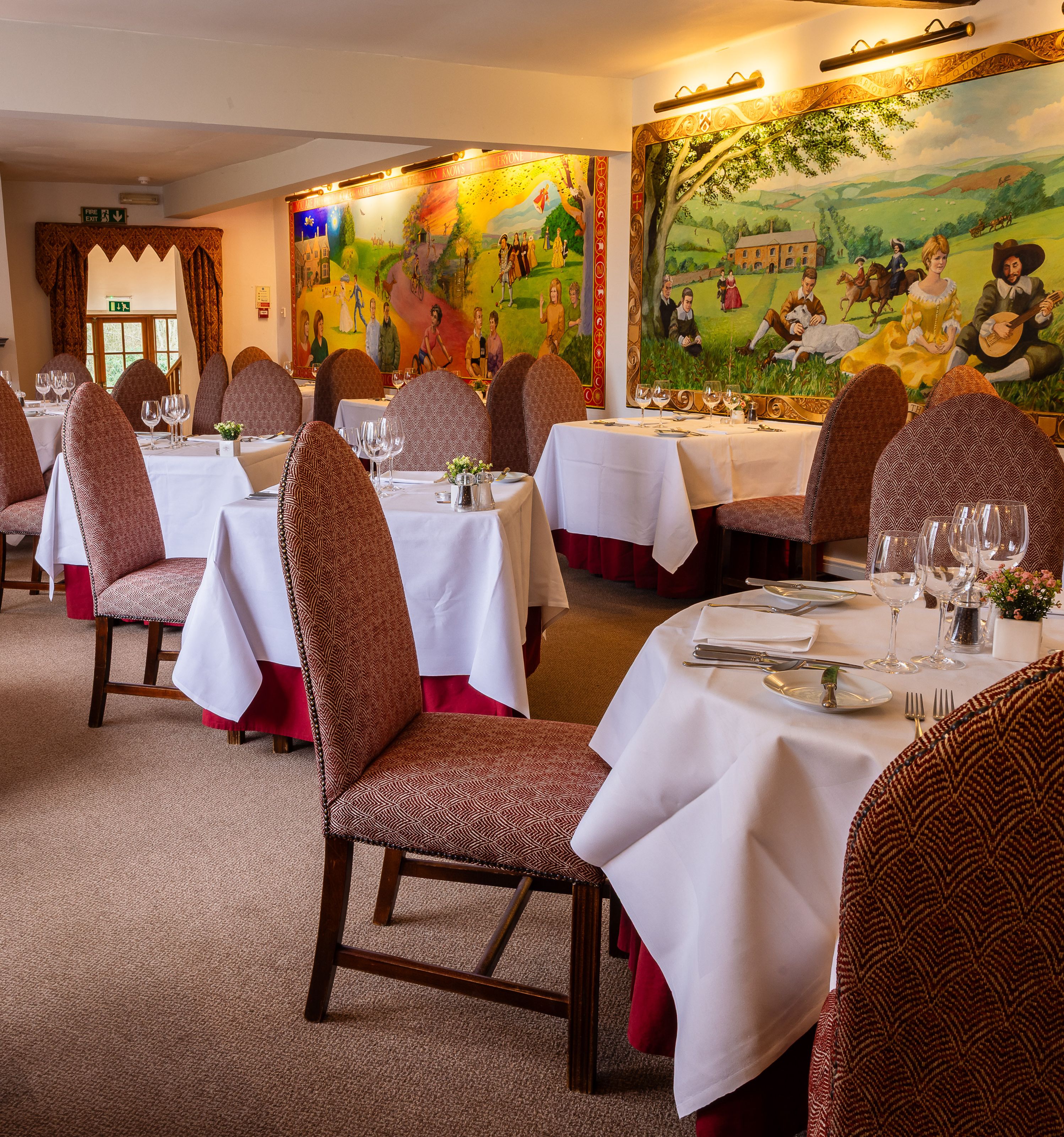 Restaurant with murals ver the walls and tablecloths on the tables