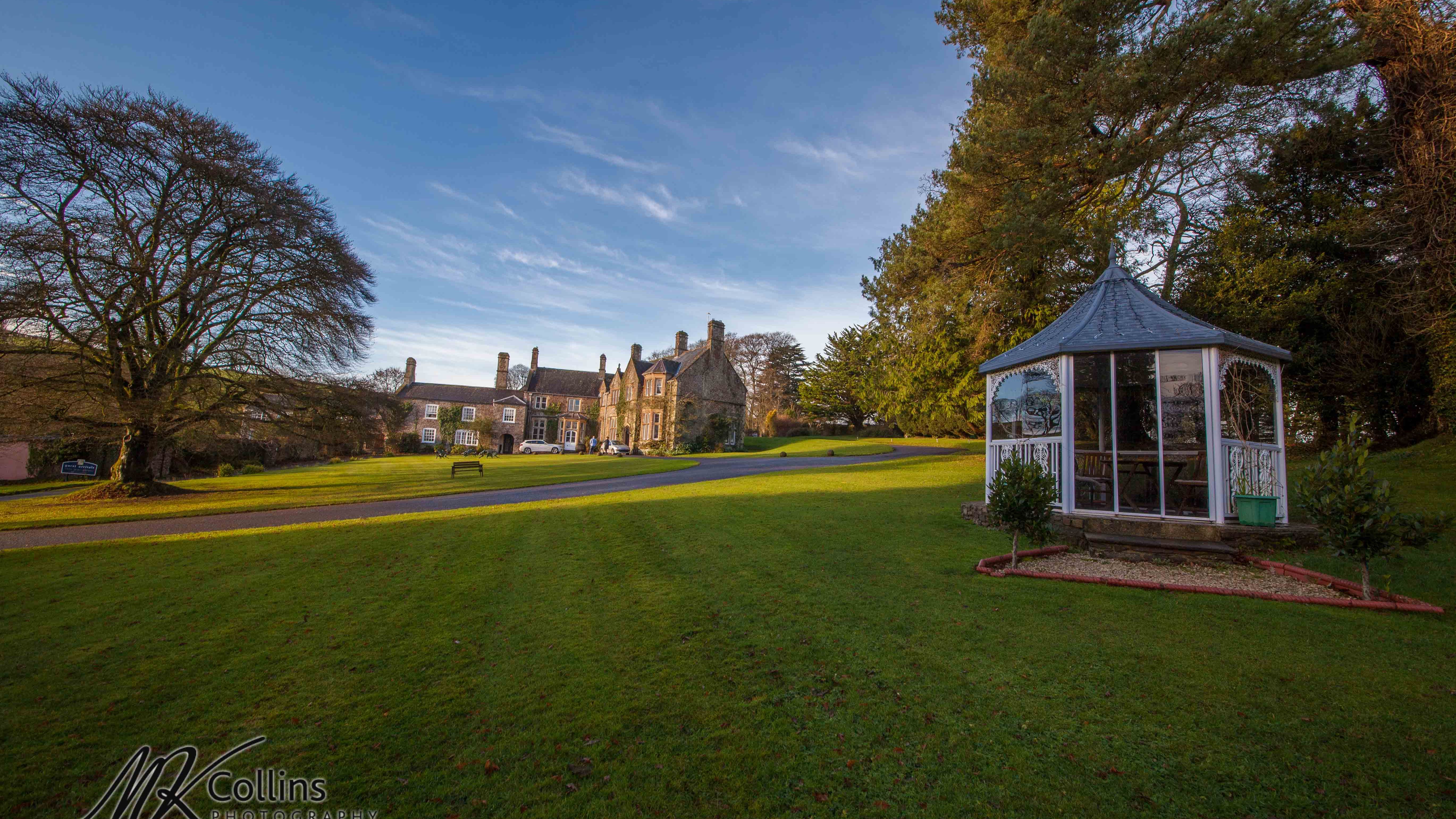 A sprawling estate with a historic stone manor sits in the background, surrounded by lush green lawns.